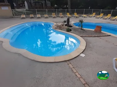 piscina con forma de riñón y tumbonas vacías en el camping de Sarrians