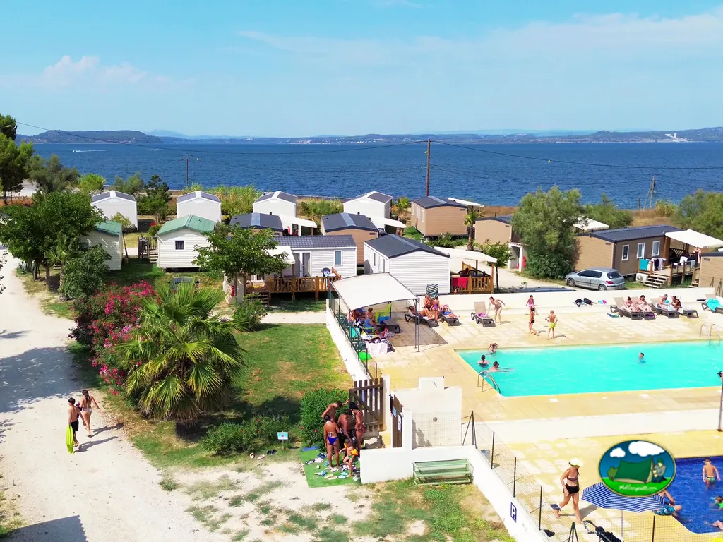 vista aérea de la piscina con bañistas y mobil-homes frente al mar en Saint-Mitre-les-Remparts
