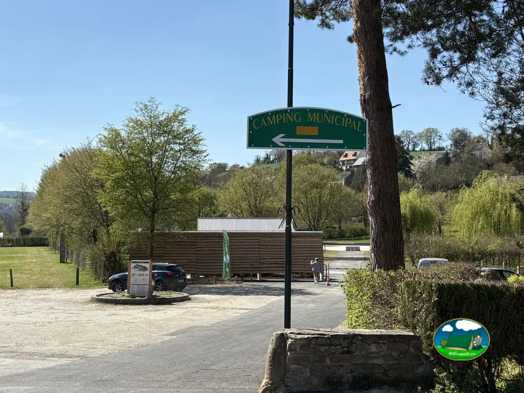 cartel de camping municipal señalando la entrada con la caseta de recepción al fondo en Pont-d'Ouilly