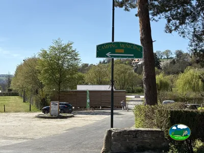 cartel de camping municipal señalando la entrada con la caseta de recepción al fondo en Pont-d'Ouilly