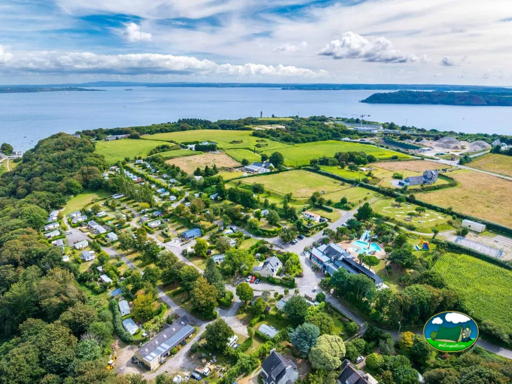 vista aérea del camping junto al mar con piscina, tobogán y parcelas arboladas cerca de Brest