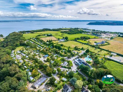 vista aérea del camping junto al mar con piscina, tobogán y parcelas arboladas cerca de Brest