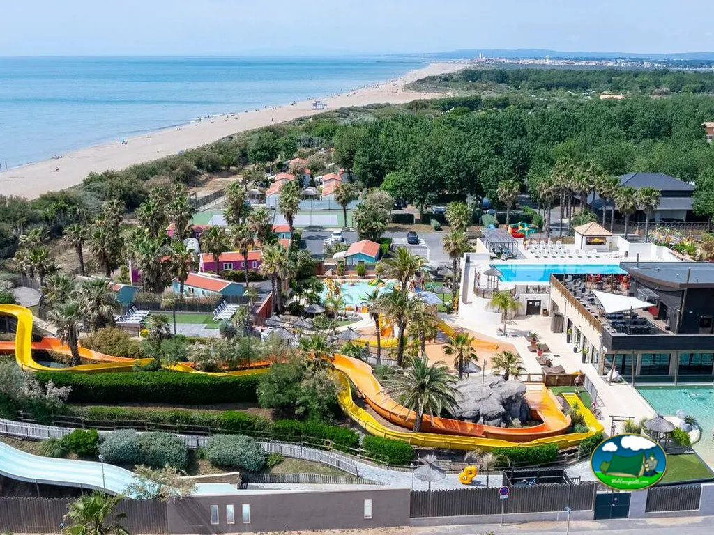 vista aérea del camping junto a la playa con toboganes acuáticos, piscinas y palmeras en Sérignan