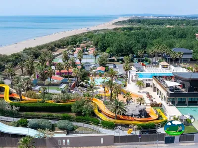 vista aérea del camping junto a la playa con toboganes acuáticos, piscinas y palmeras en Sérignan