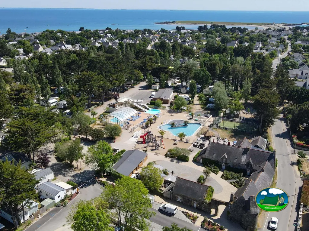 vista aérea del camping con piscina cubierta, parque infantil y el mar de fondo