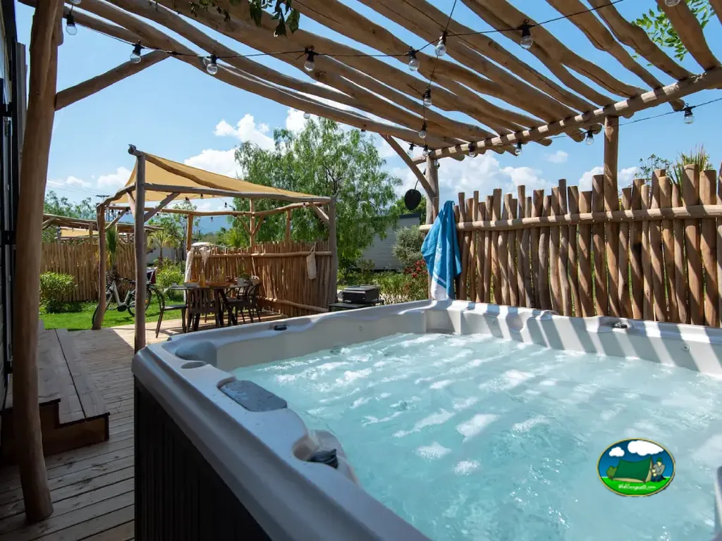 jacuzzi exterior bajo una pérgola de madera con luces de guirnalda