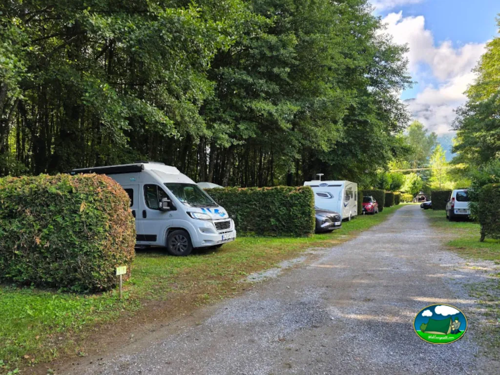 camino de grava entre parcelas con autocaravana y caravana bajo montañas en Lathuile