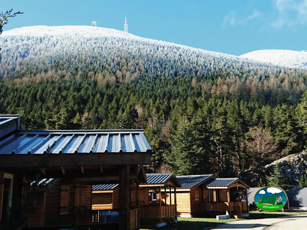 cabañas de madera con tejado oscuro frente al Mont Ventoux nevado