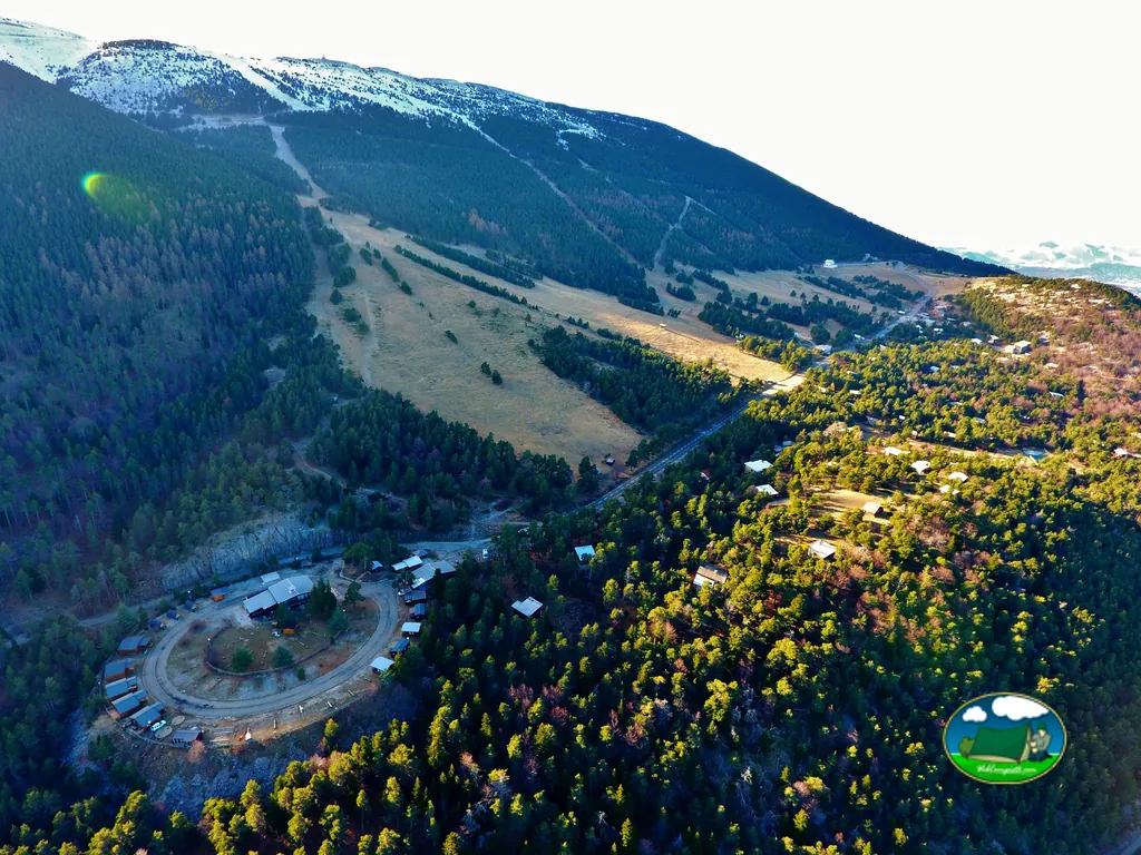 vista aérea de una estación de montaña nevada con el camping junto a la carretera