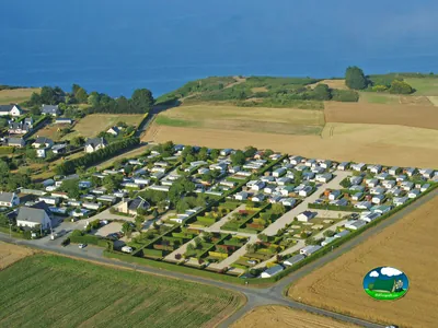 vista aérea del camping junto al mar con parcelas de mobil-homes entre campos de cultivo en Pordic