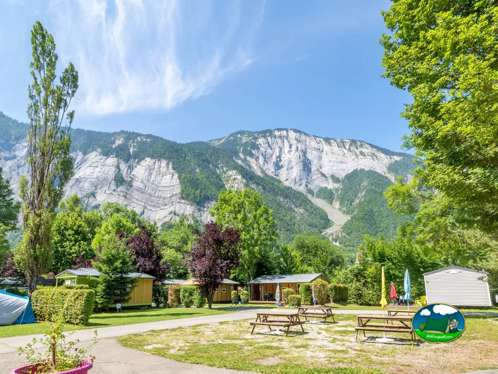 mesas de picnic y mobil-homes con las montañas de fondo en Le Bourg-d'Oisans