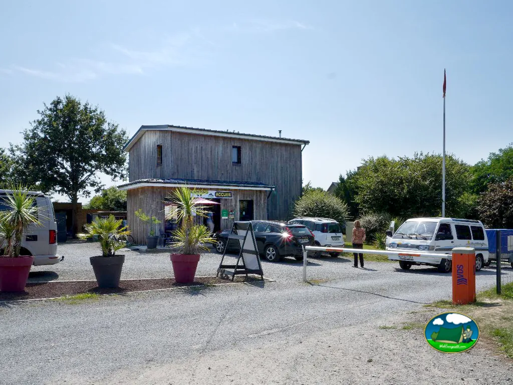 edificio de recepción con cartel camping accueil, coches aparcados y barrera de acceso en Céaux
