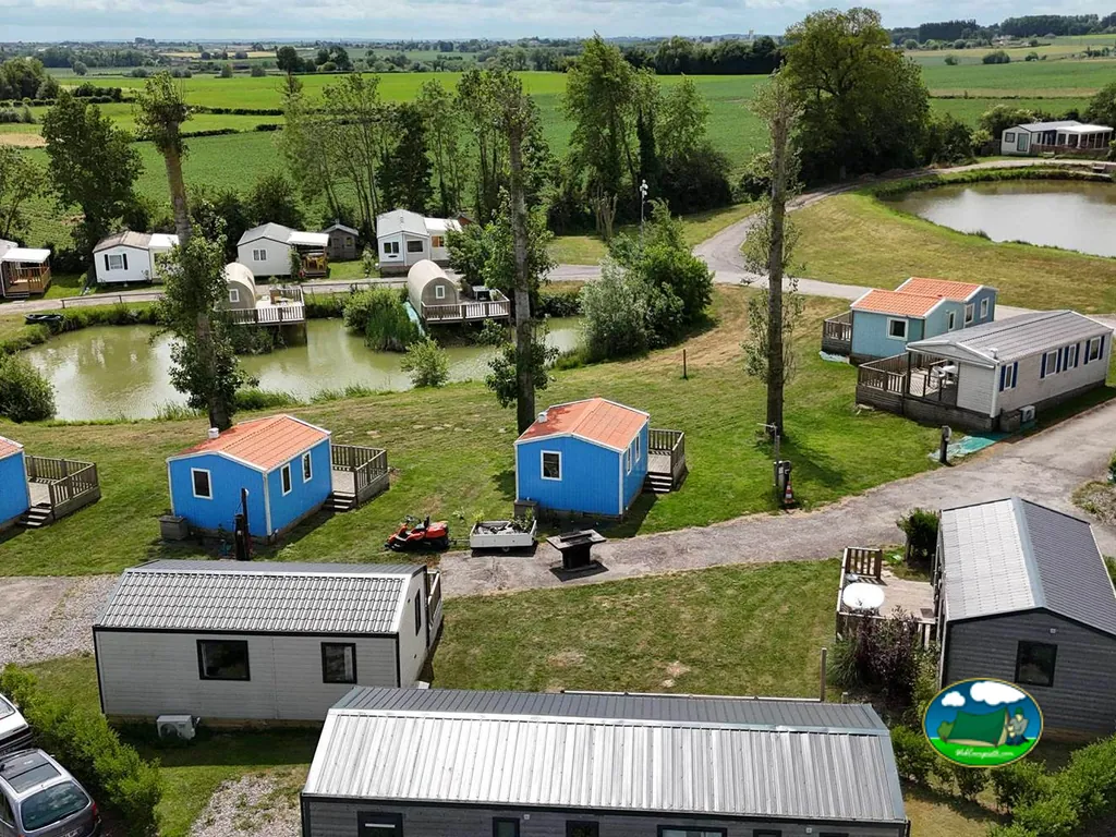 vista aérea de cabañas azules y casas móviles junto a dos estanques y campos verdes en Steenvoorde