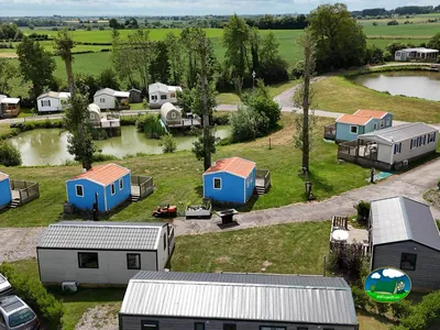 vista aérea de cabañas azules y casas móviles junto a dos estanques y campos verdes en Steenvoorde