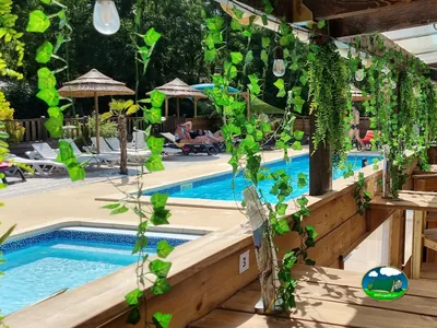 piscina con pérgola de enredaderas y tumbonas junto a personas relajándose en Ruoms