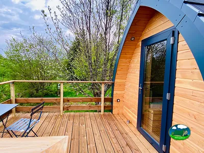 terraza de madera de una cabaña abovedada con mesa y sillas en Saint-Urcize