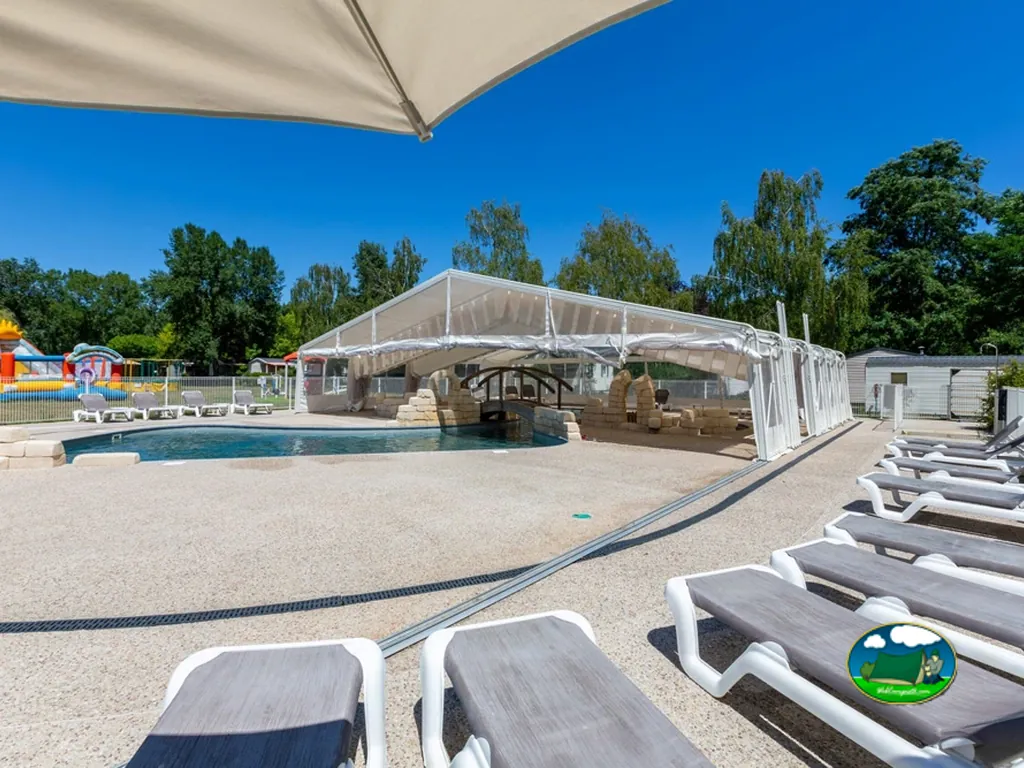 piscina con cubierta retráctil y tumbonas junto a un hinchable infantil de colores
