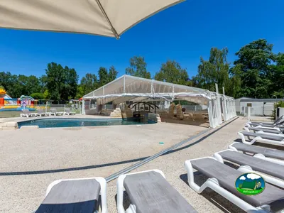 piscina con cubierta retráctil y tumbonas junto a un hinchable infantil de colores
