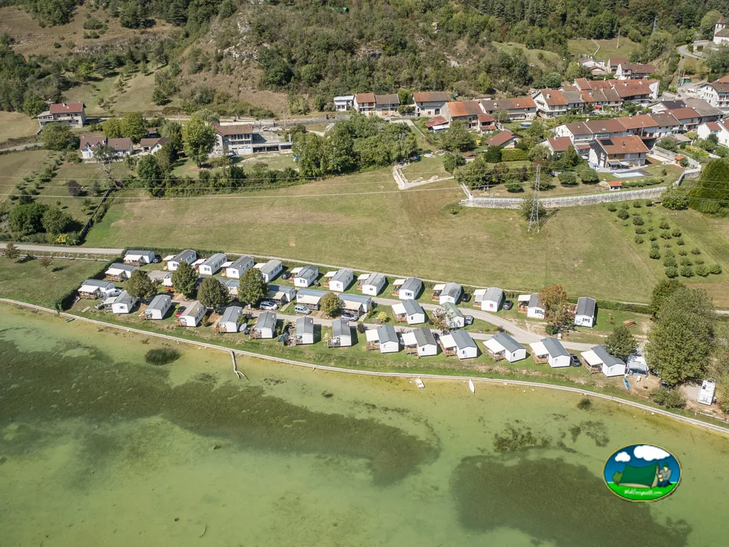 vista aérea de hileras de bungalows junto al lago con el pueblo y las montañas al fondo