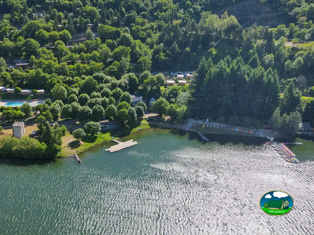 vista aérea del camping junto al lago con piscina, embarcadero de troncos y piraguas de colores en Pourcharesses