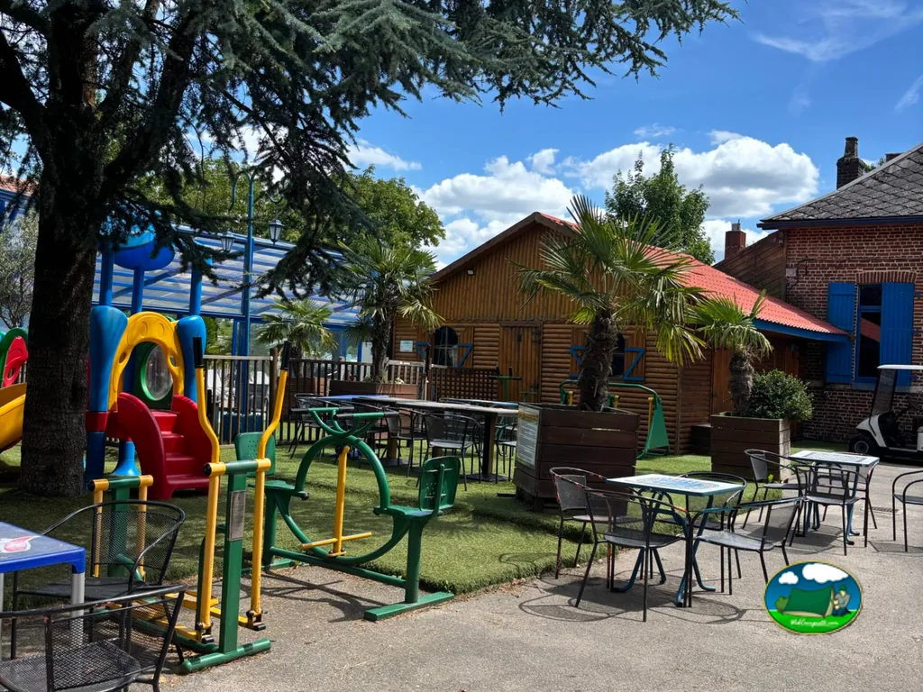zona infantil con tobogán junto a mesas de terraza, palmeras y un carrito de golf en Renty