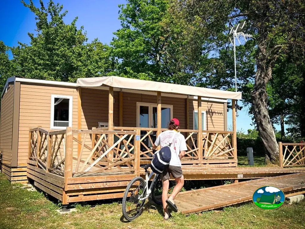 persona de espaldas con bicicleta accediendo a un bungalow de madera por una pasarela elevada