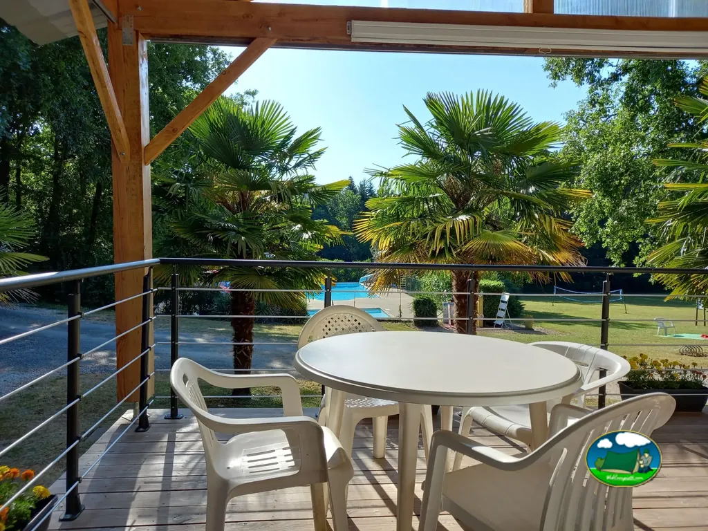 terraza cubierta con mesa y sillas blancas con vistas a la piscina y las pistas de deporte entre palmeras