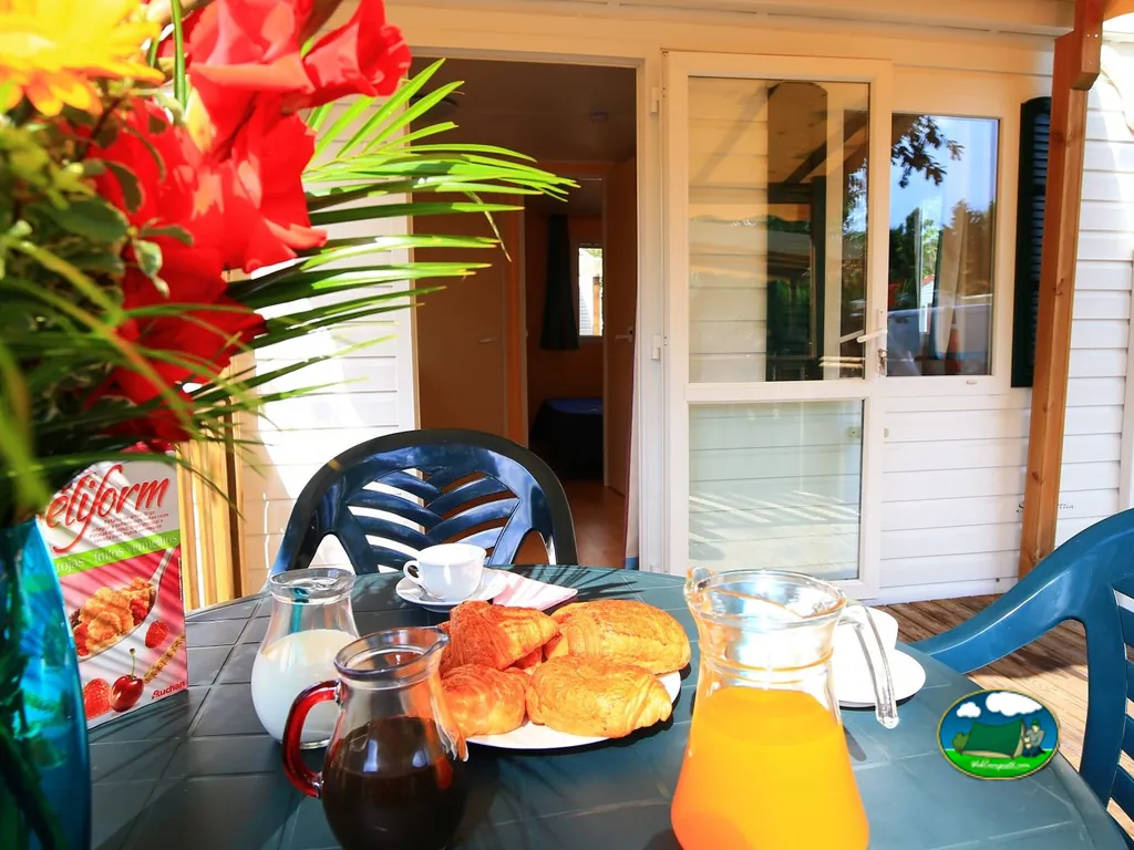 mesa de desayuno con cruasanes, zumo de naranja y café en la terraza de un bungalow