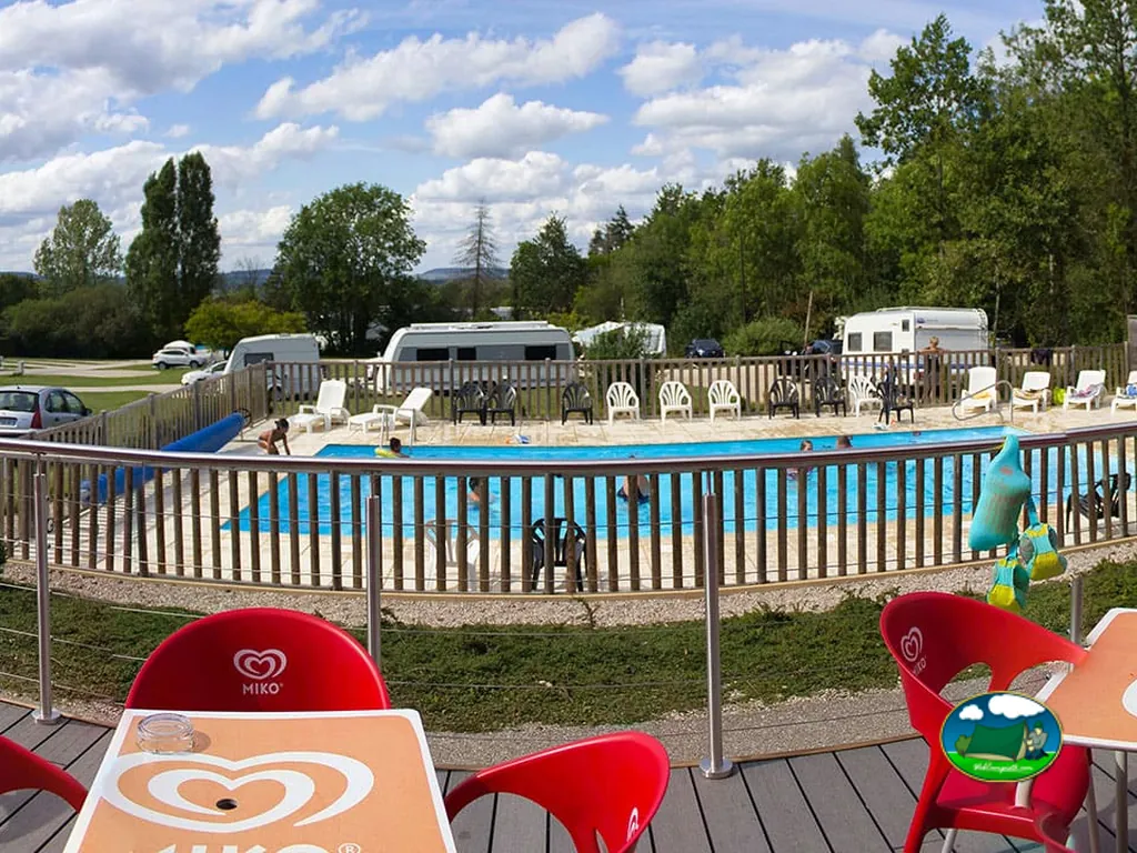 piscina del camping vista desde la terraza con bañistas y caravanas aparcadas al fondo