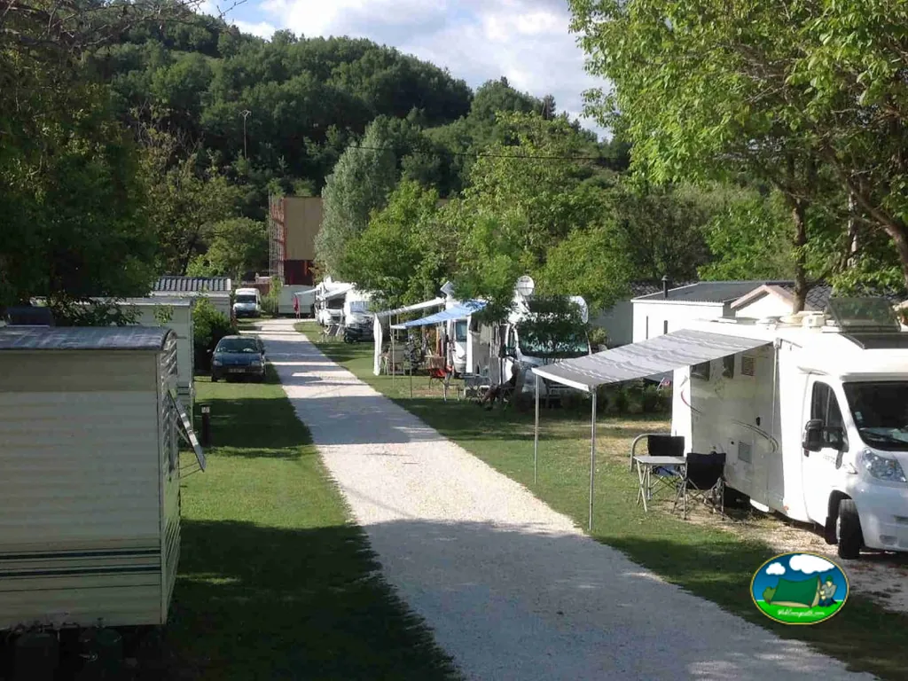 camino de grava entre parcelas con caravanas y autocaravanas bajo los árboles en Castellane