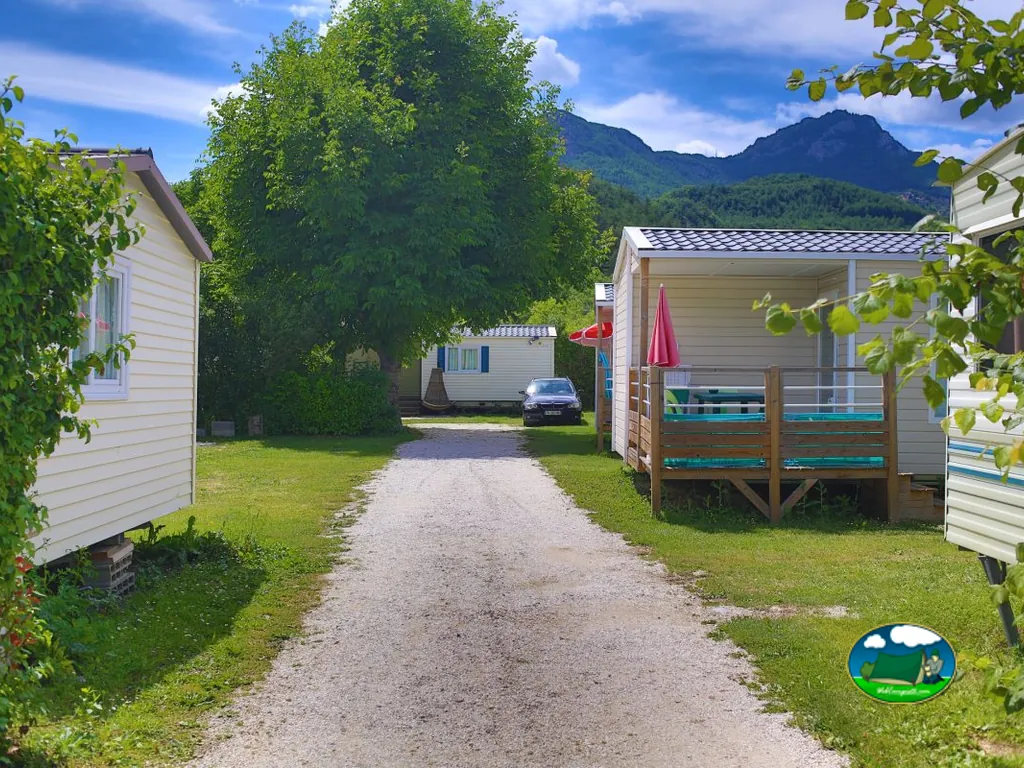 camino de grava entre chalets del camping con las montañas al fondo en Castellane