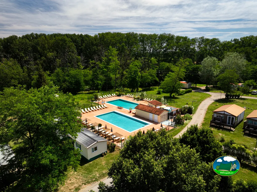 vista aérea de dos piscinas rodeadas de árboles y chalets en el camping de Mazères