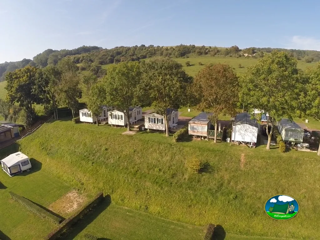 hilera de casas móviles del camping bajo árboles junto a una loma verde en Criel-sur-Mer