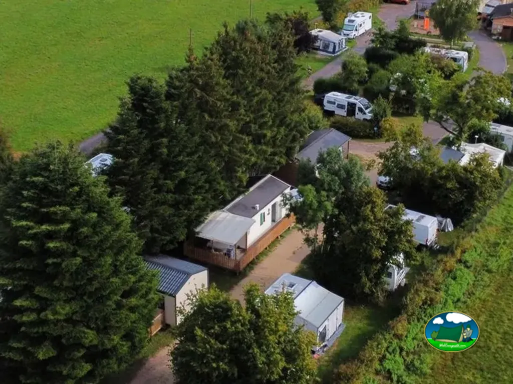 casas móviles y autocaravanas del camping entre árboles junto a un camino de tierra en La Vôge-les-Bains
