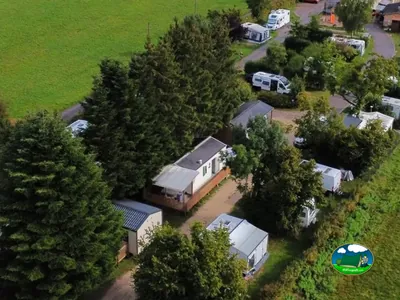 casas móviles y autocaravanas del camping entre árboles junto a un camino de tierra en La Vôge-les-Bains