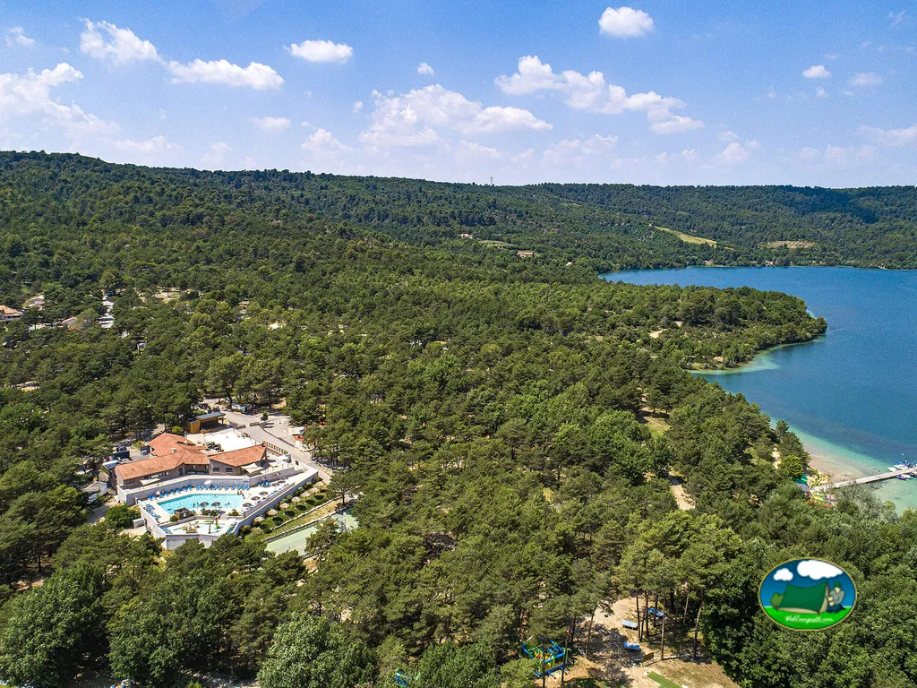 vista aérea del camping con piscina y edificios de tejas rodeado de pinar junto al lago de Sainte-Croix