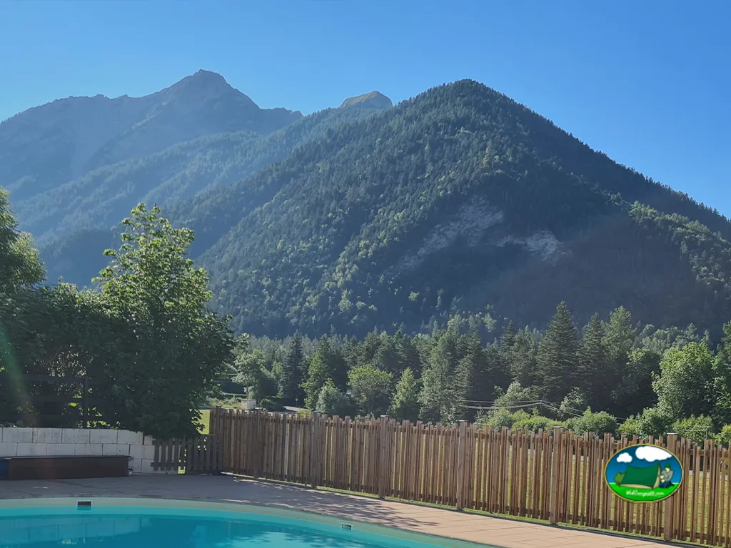 borde de la piscina del camping con vallado de madera y vistas a las montañas de los Alpes en Ancelle
