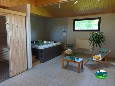 sala de spa del camping con jacuzzi, sauna de madera y tumbonas junto a una ventana
