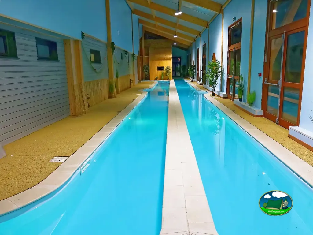 piscina cubierta alargada con tumbonas junto a las cristaleras del camping