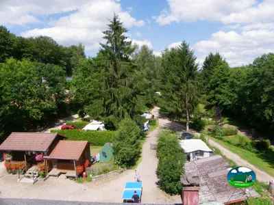 vista aérea del camping en Plombières-les-Bains con chalés, tiendas y una mesa de ping-pong entre los árboles
