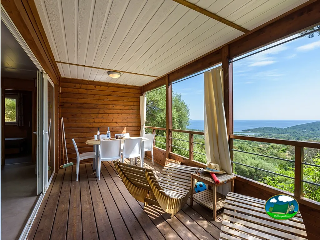 terraza de madera con mesa y tumbonas con vistas al mar desde una casa móvil del camping en Porto-Vecchio