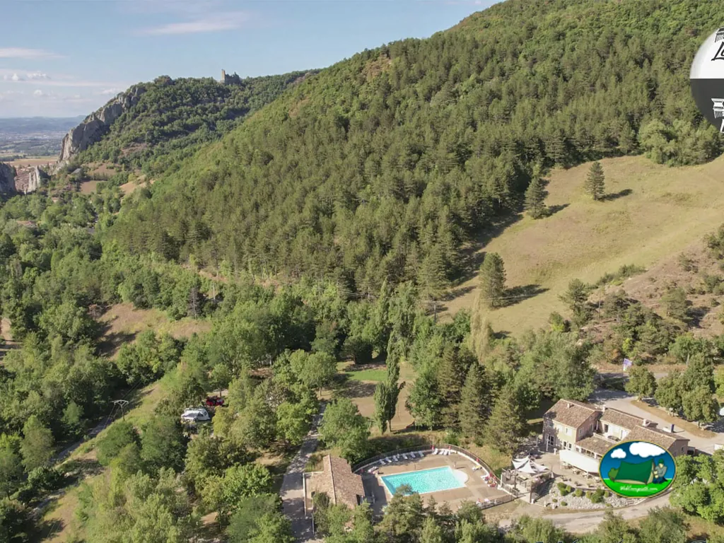 vista aérea del camping en Barbières con piscina y edificios rodeados de colinas boscosas