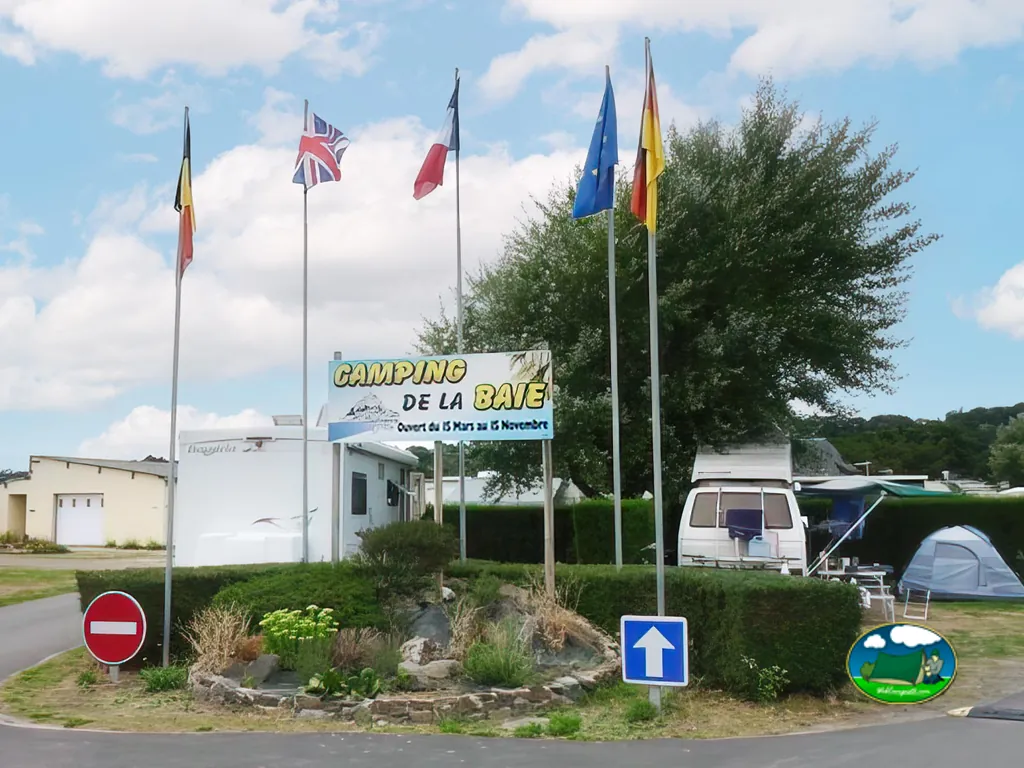 entrada del camping con banderas, cartel Camping de la Baie y autocaravana aparcada