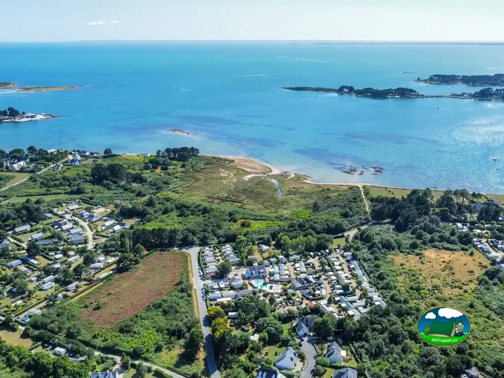 vista aérea de la costa con la piscina y los bungalós del camping entre la vegetación en Locmariaquer