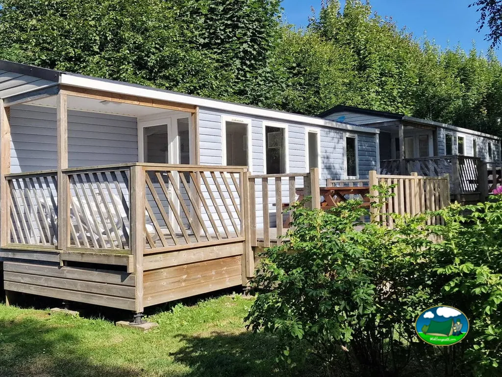 hilera de mobil-homes con terrazas de madera junto a un seto verde