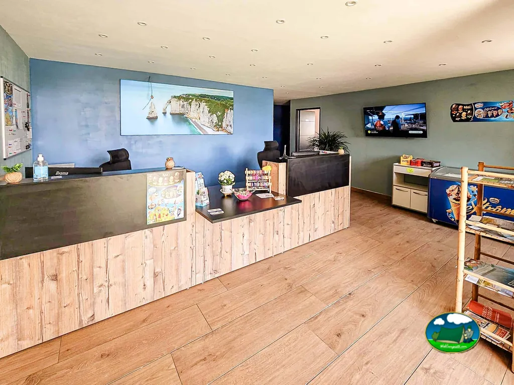 recepción del camping con mostrador de madera, televisor y expositor de helados