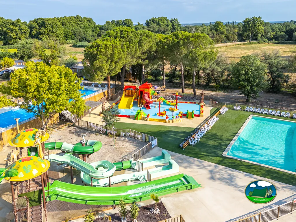 vista aérea del parque acuático con toboganes, piscina infantil y piscina grande rodeada de tumbonas en Vauvert