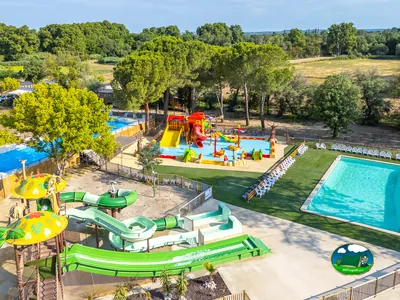 vista aérea del parque acuático con toboganes, piscina infantil y piscina grande rodeada de tumbonas en Vauvert