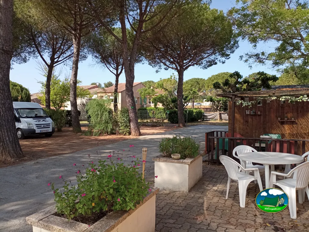 furgoneta camper aparcada junto a parcelas arboladas y una terraza con mesa y sillas en Creissan