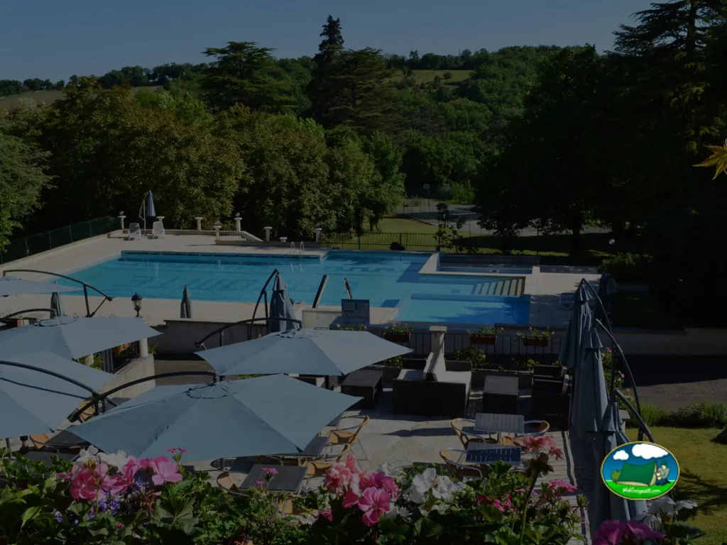 piscina con sombrillas y tumbonas al atardecer entre los jardines del château en Carlucet